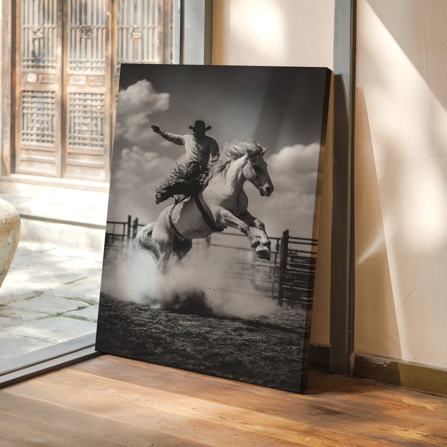 Canvas print of a cowboy on a horse leaping over a fence in a room with a wooden floor and glass door.