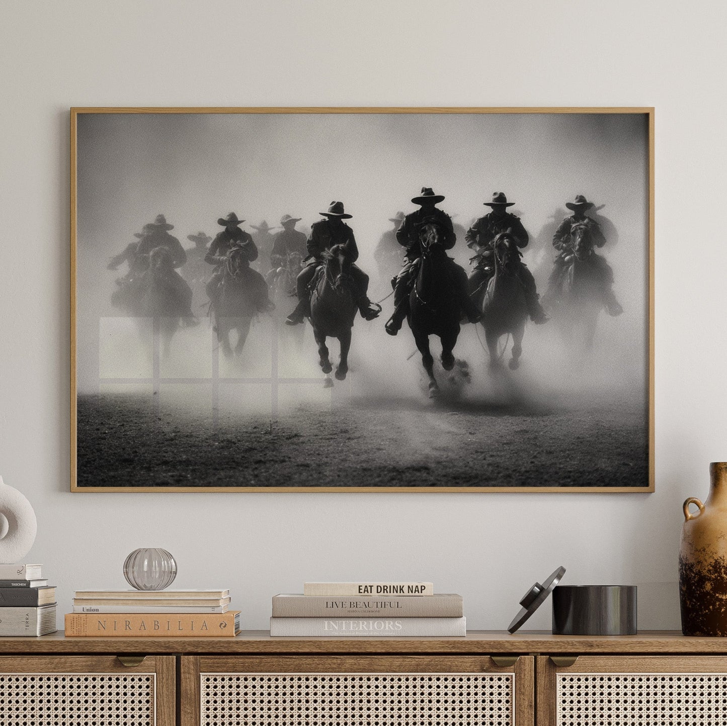Wooden cabinet with decorative items and a framed black and white artwork of horses on a wall.