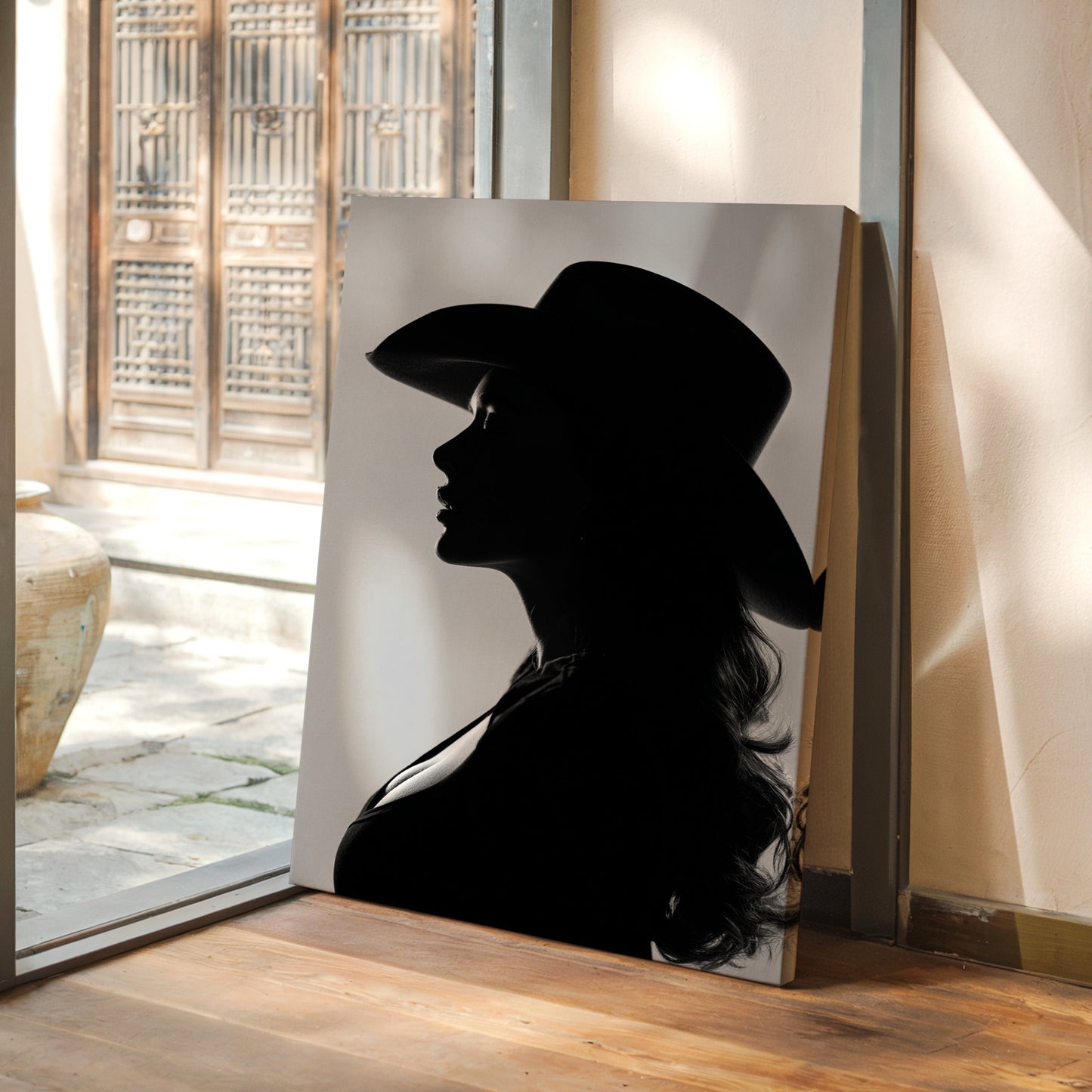 Silhouette of a person wearing a hat on a wall in a room with a view of a courtyard.