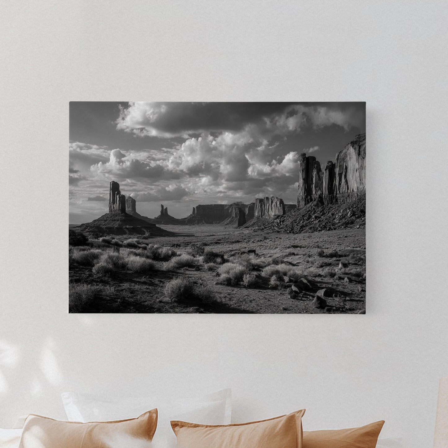 Black and white landscape print on a wall above a bed with beige pillows.