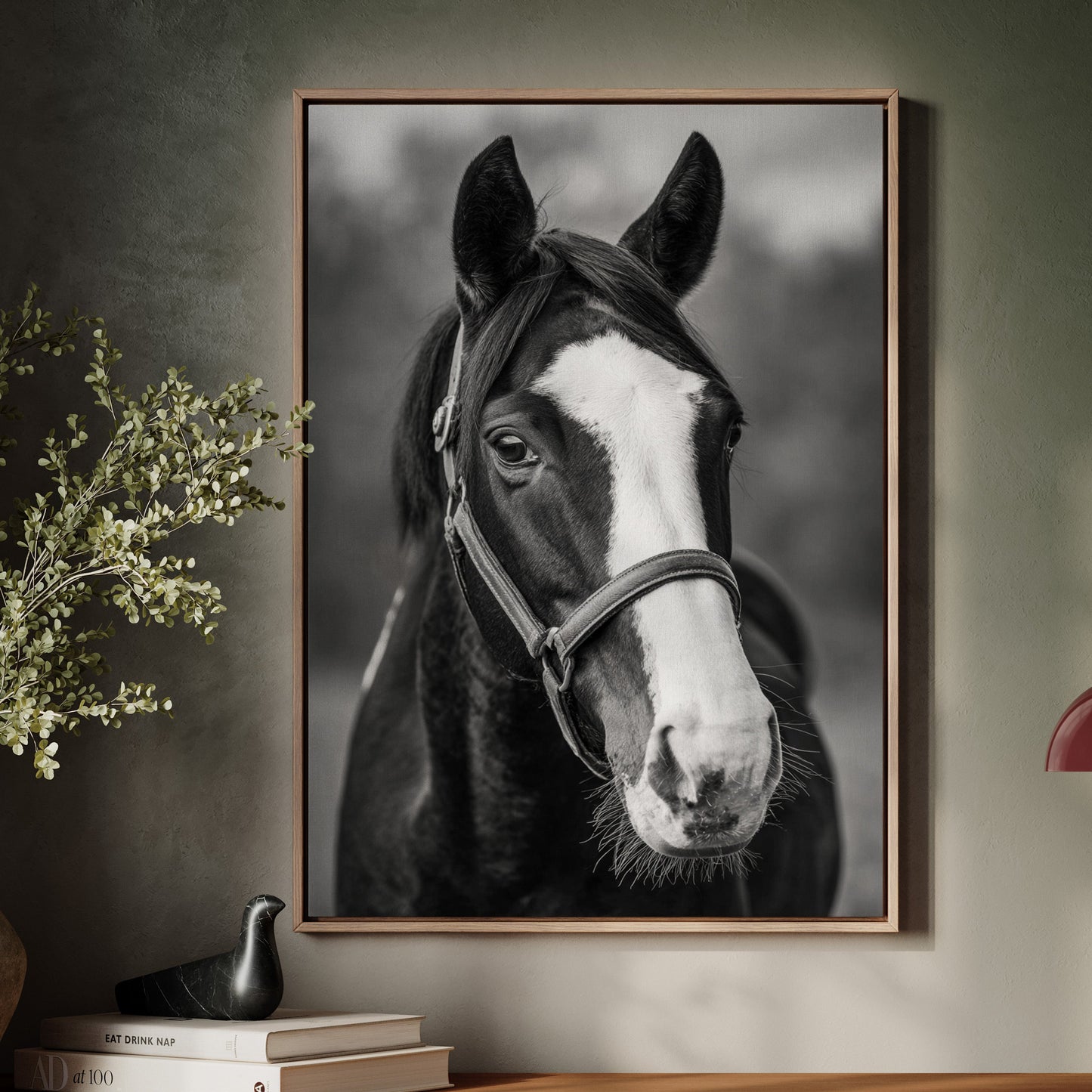 Framed black and white horse portrait on a wall above a wooden cabinet with decor items.