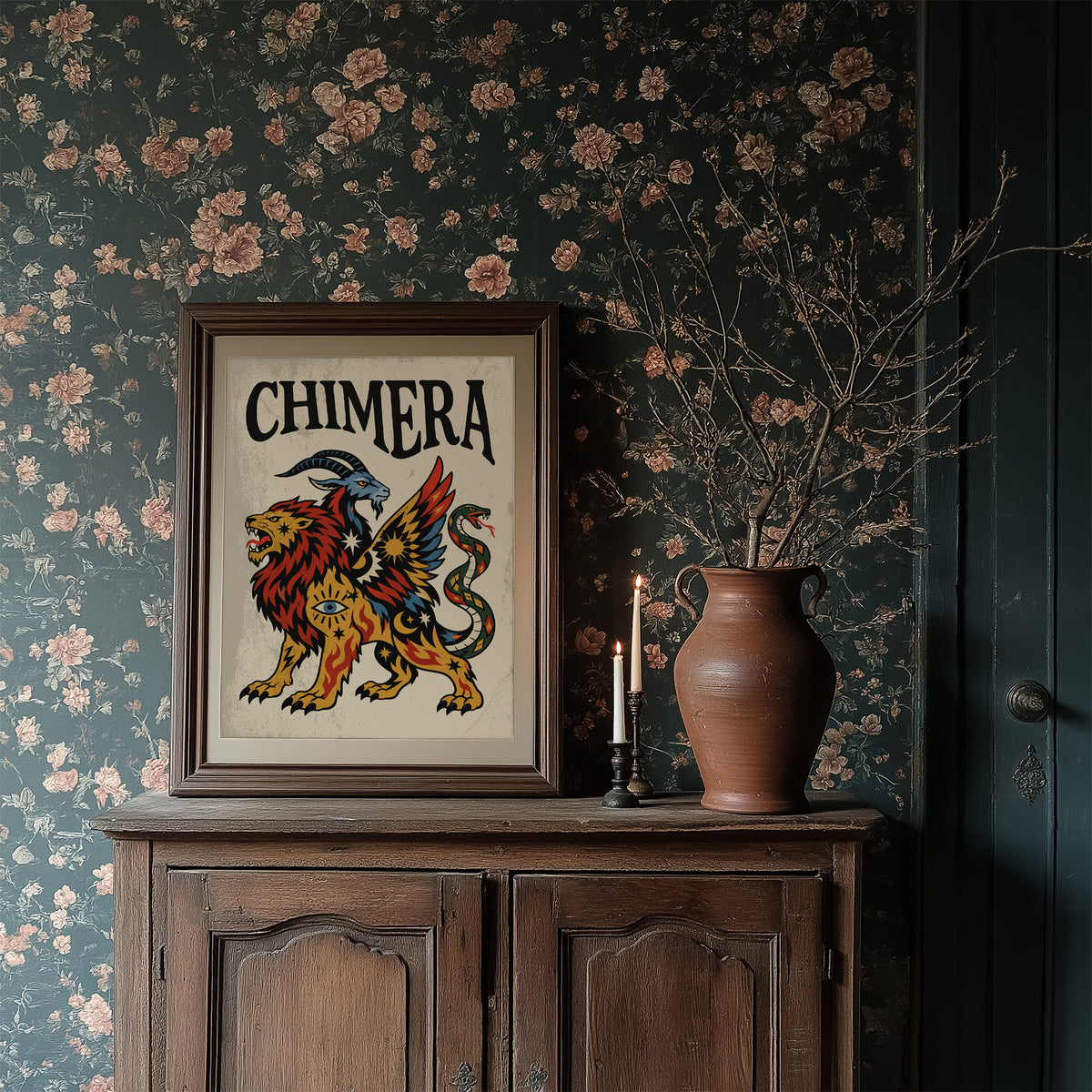 A Beast Made of Borrowed Parts, a chimera with a lion body, a goat head and a serpent tail, in gold, red and cream, drawn in a bold flash sheet style with a black lettered name across the top, in a dark wood frame on a floral wallpaper wall above a rustic cabinet and a vase