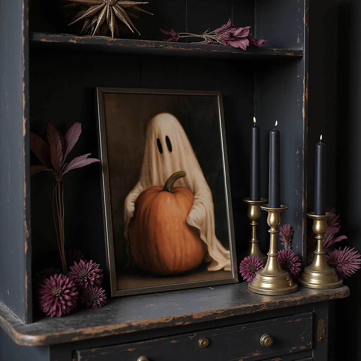 A Sheet Holds the Pumpkin Still, a pale draped figure holding a large orange pumpkin close, in a dark brown painted frame with a warm glow, in a dark frame on a black shelf beside brass candles and dried leaves