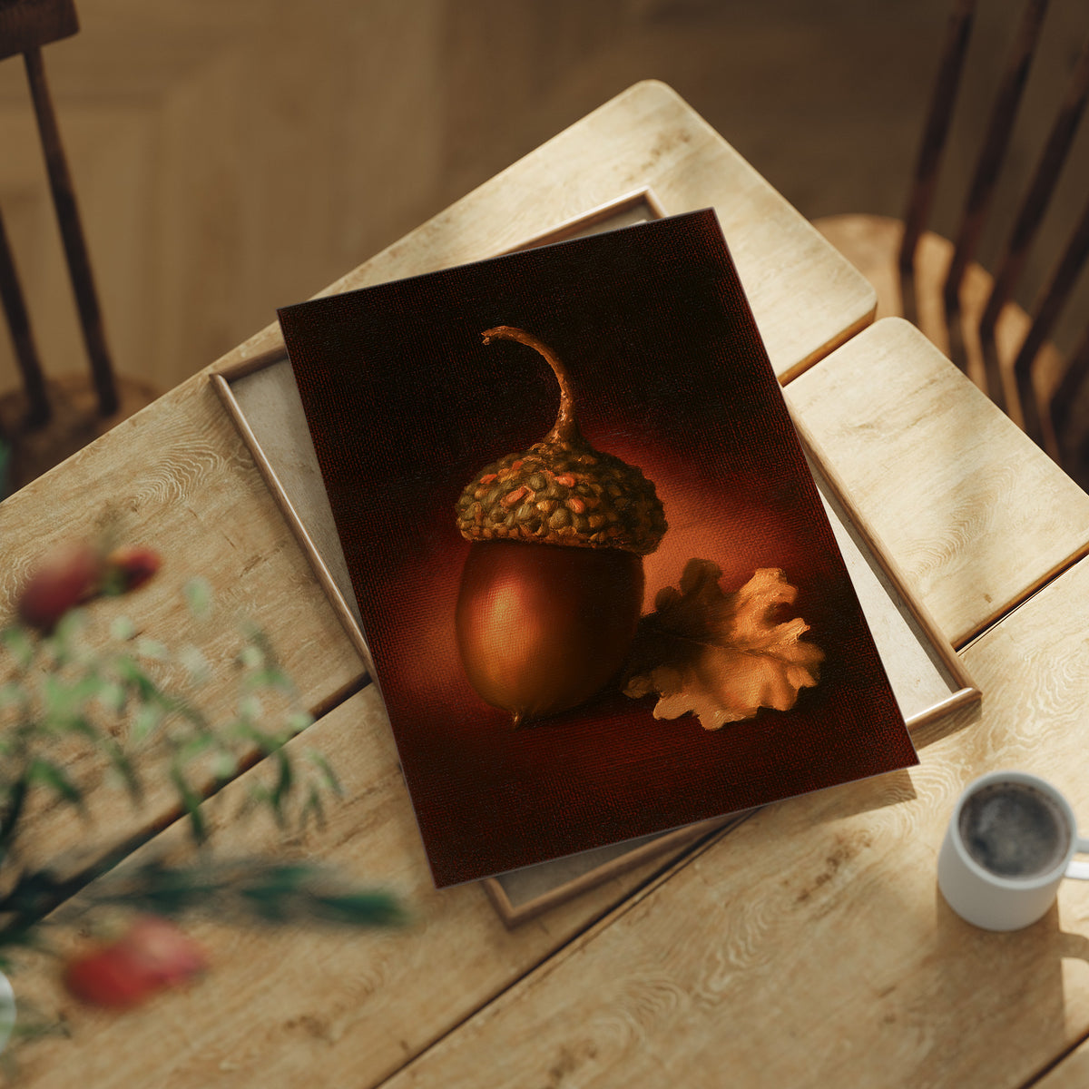 A Single Acorn in Candlelight, one acorn resting beside a curled oak leaf on a dark brown ground, lit from one side and painted in chestnut, amber and deep shadow, lying flat on a light wood table beside a coffee cup and red berries