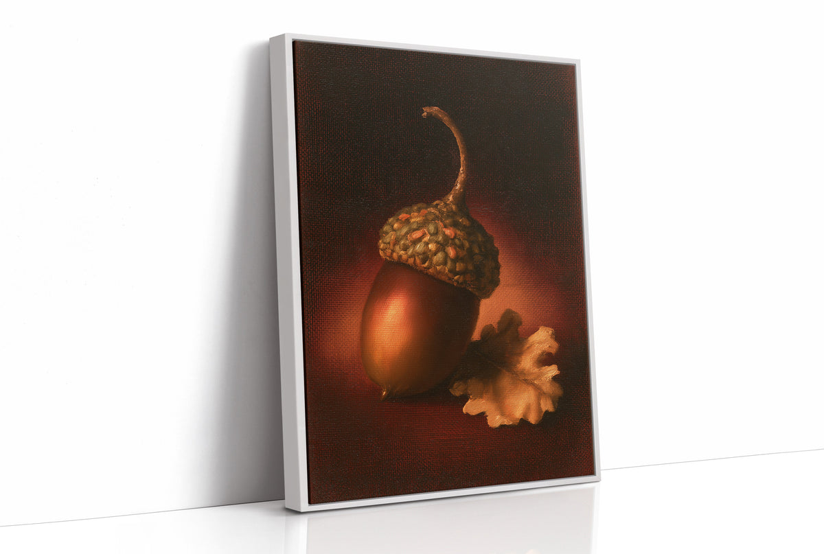 A Single Acorn in Candlelight, one acorn resting beside a curled oak leaf on a dark brown ground, lit from one side and painted in chestnut, amber and deep shadow, as a framed canvas in a white frame