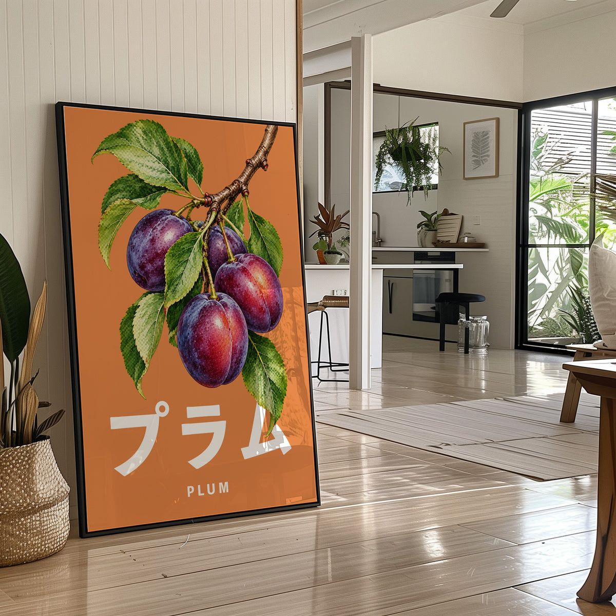 Branch Heavy with Plums, a branch of purple plums with green leaves on a burnt orange ground, with a tall block of Japanese katakana and the English word PLUM set small in cream beneath, in a black frame leaning on a bright hallway floor beside a potted plant