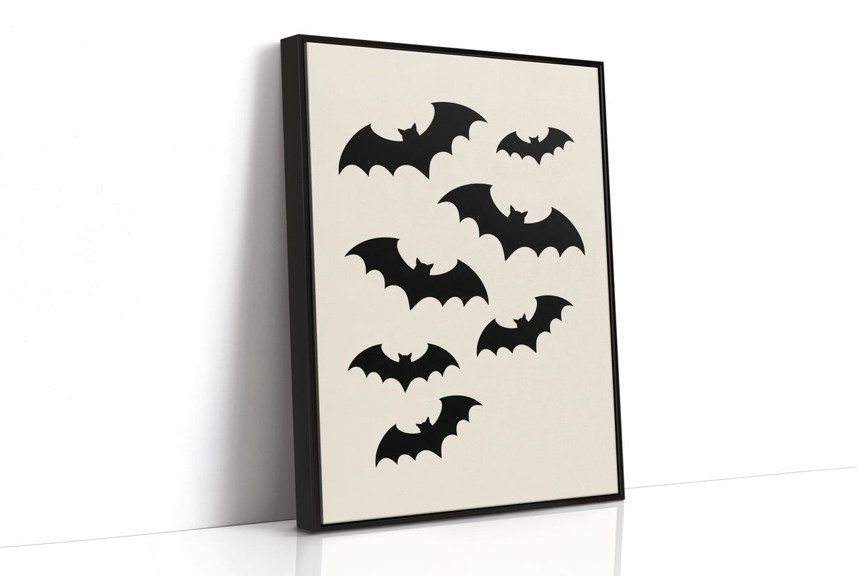 Evening Flight in Silhouette, a loose flock of black bat silhouettes spread across a cream ground in a simple, flat graphic arrangement, as a framed canvas in a black frame