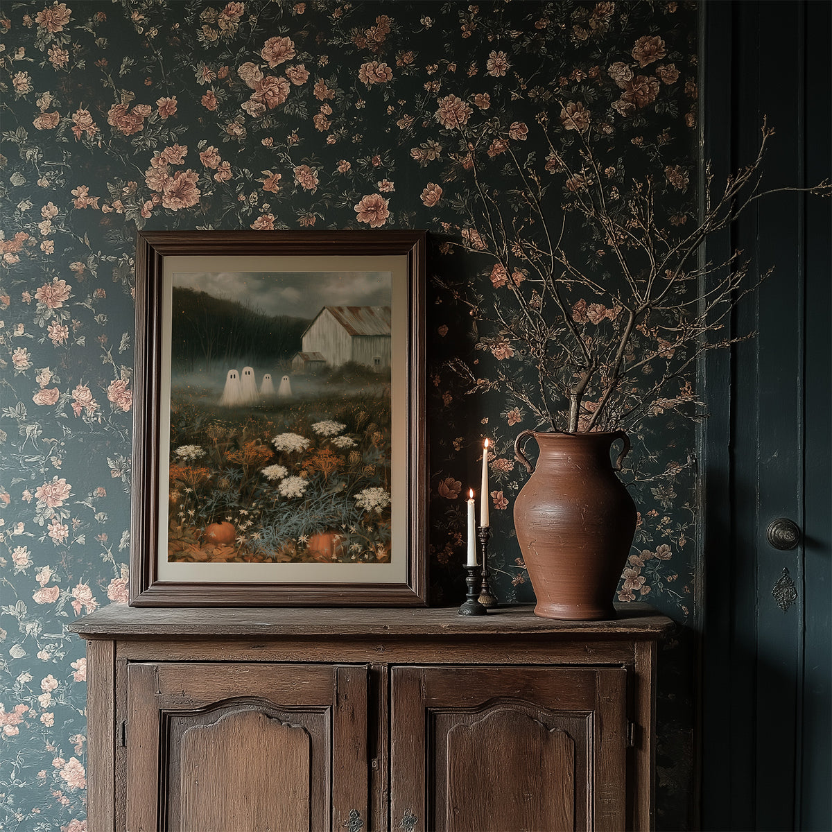 Fog Settles on the Low Field, a dark barn on a hill above a meadow of cream and rust wildflowers, a pale mist in the valley and two faint pale figures at the edge of the field, painted in forest green, rust and bone, in a dark wood frame on a floral wallpaper wall above a rustic cabinet and a vase