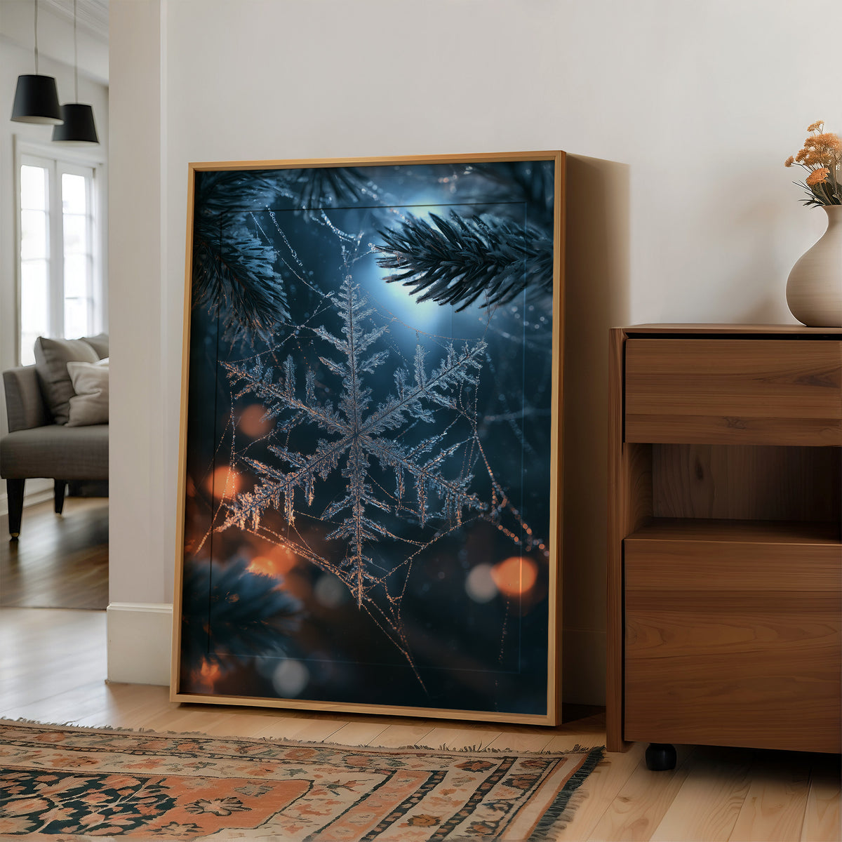 Frost Keeps Its Own Hours, a frost snowflake laid over a pine bough at night, with warm bokeh lights in navy, silver and amber, in a wood frame on a wall beside a walnut cabinet and an open doorway