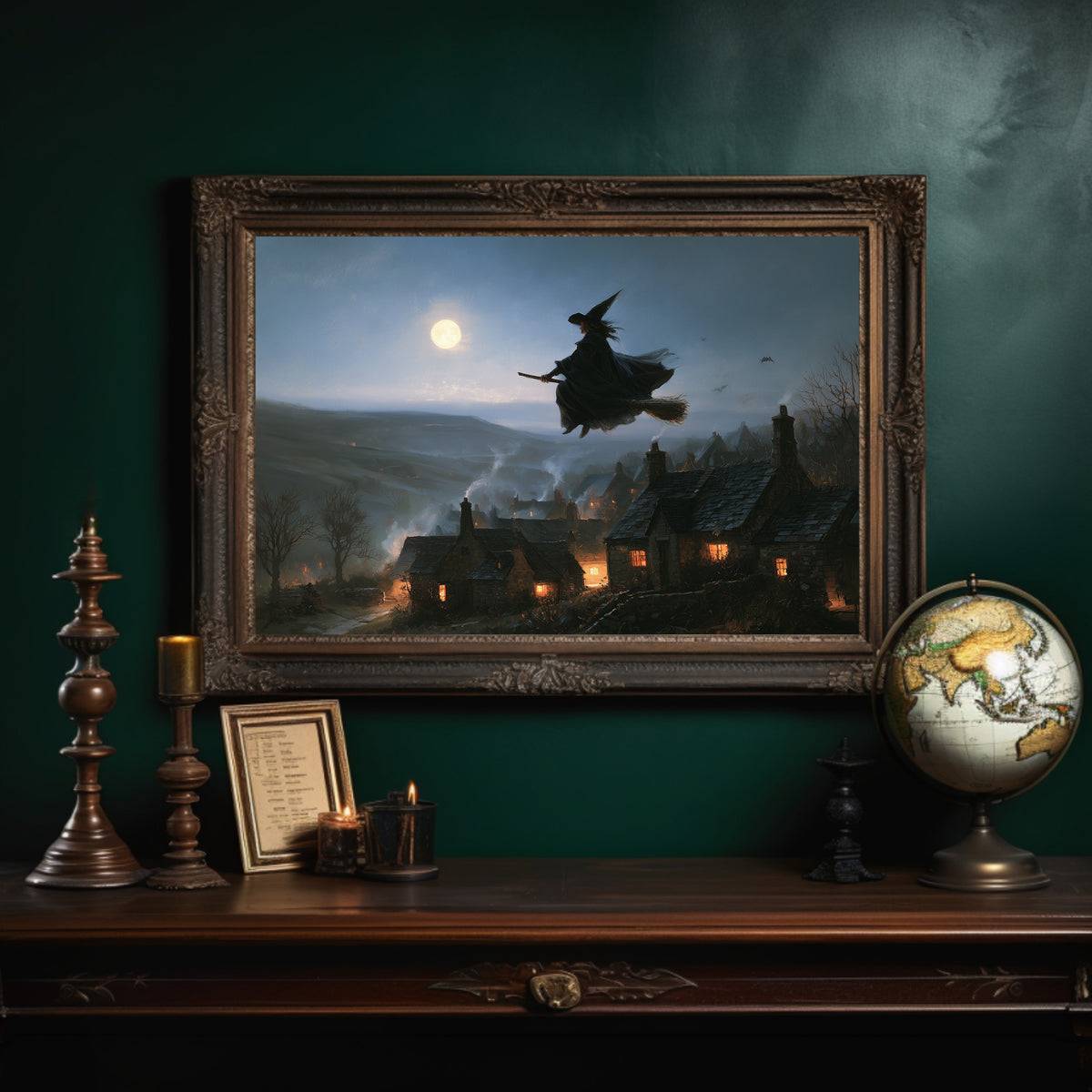 Over the Lantern Village, a witch flying across a full moon above a lantern lit village on a misty hillside, painted in midnight blue, pale moon gold and soft smoke gray, in an ornate dark frame on a deep green wall above a mantel with a globe and candles