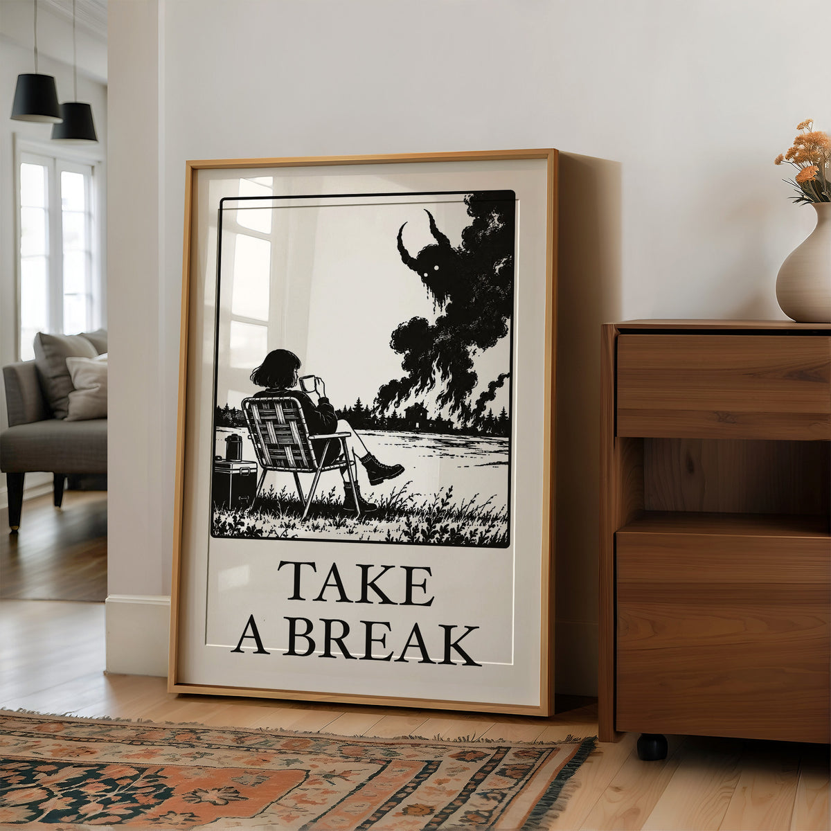 The Break Nobody Schedules, a figure in a deck chair under a broad tree in a black and cream line scene, with TAKE A BREAK in large serif capitals beneath, in a wood frame on a wall beside a walnut cabinet and an open doorway