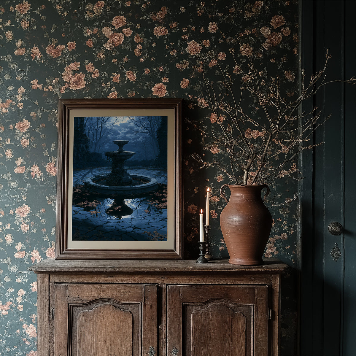 The Fountain Holds Its Breath, moonlit garden fountain painting in deep blue, in a dark frame on a wooden dresser against floral wallpaper