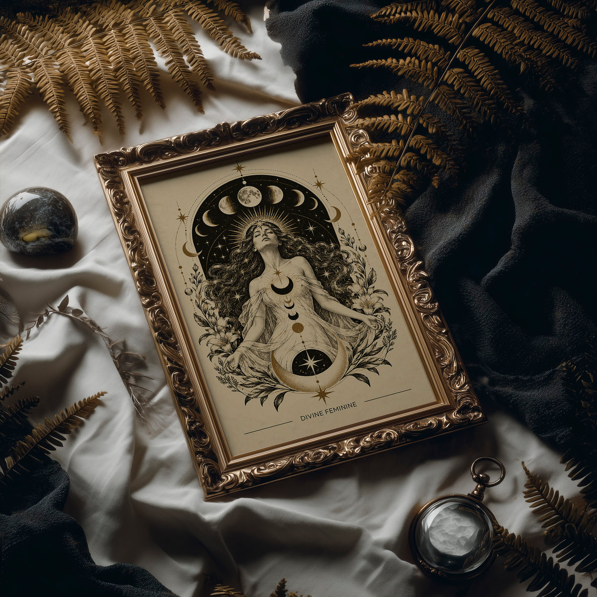 The Moon Woven Into Her Hair, a seated woman in quiet meditation crowned with a ring of crescent moons and surrounded by fern fronds, drawn in cream, charcoal and sepia with a deep brown border and small text at the base, in an ornate frame on silk cloth beside ferns and a brass compass