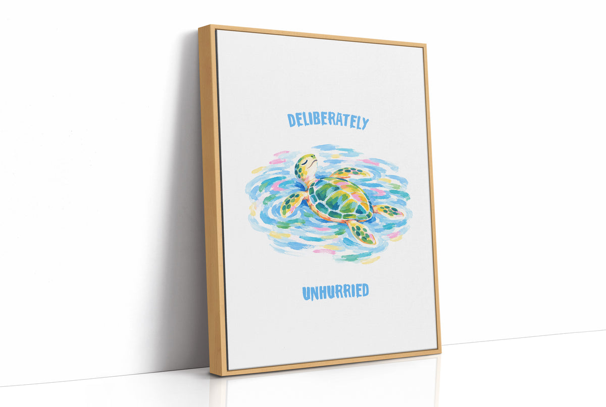 The Turtle Keeps Its Own Time, a sea turtle drifting over pale blue and green watercolor waves, with two lines of bold blue lettering above and below it on a white ground, in a soft watercolor style, as a framed canvas in a natural wood frame