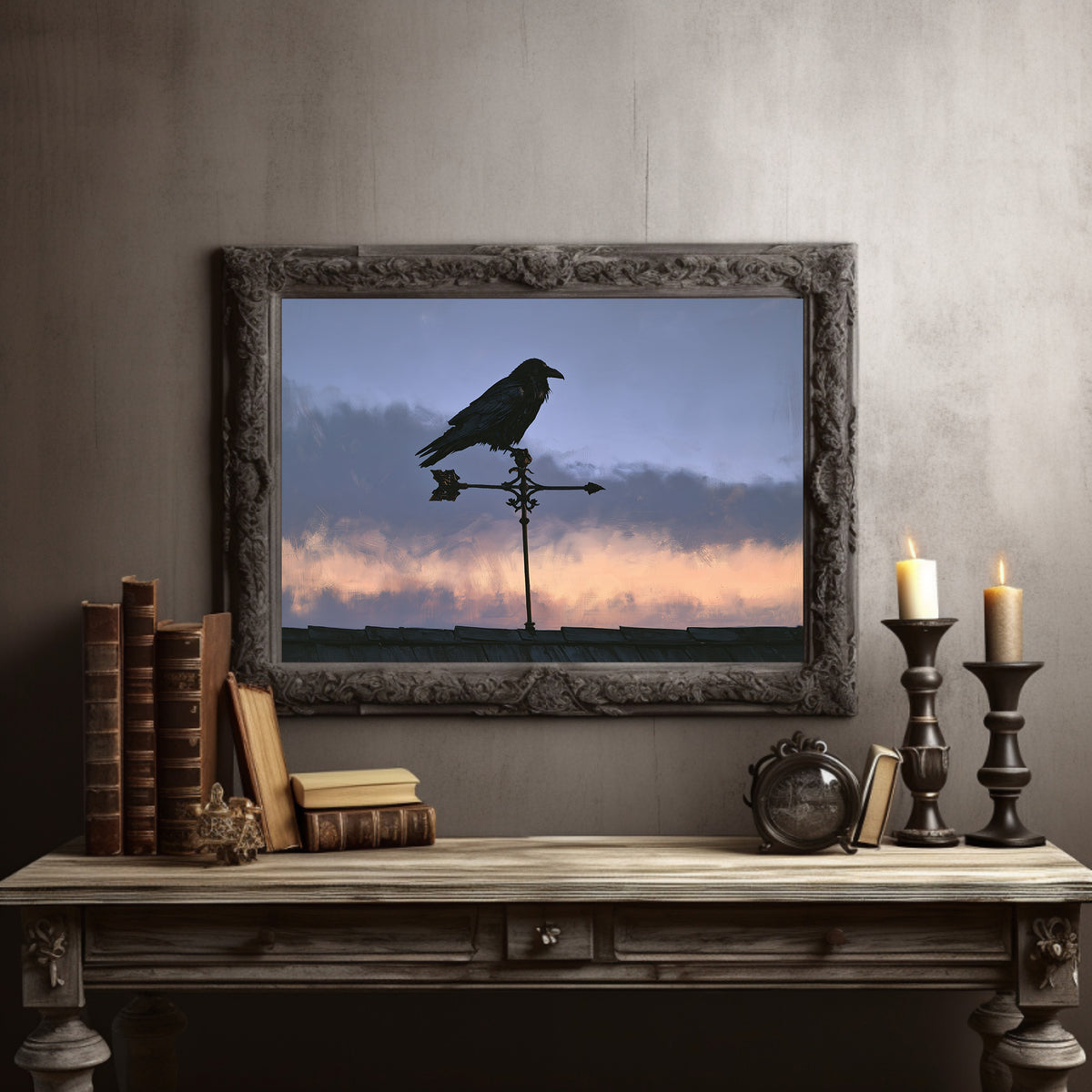 Watcher on the Weathervane, a black raven perched on a weathervane against a dusk sky banded in dusky blue and rose, in a dark carved frame on a gray wall above a console table with candlesticks and old books