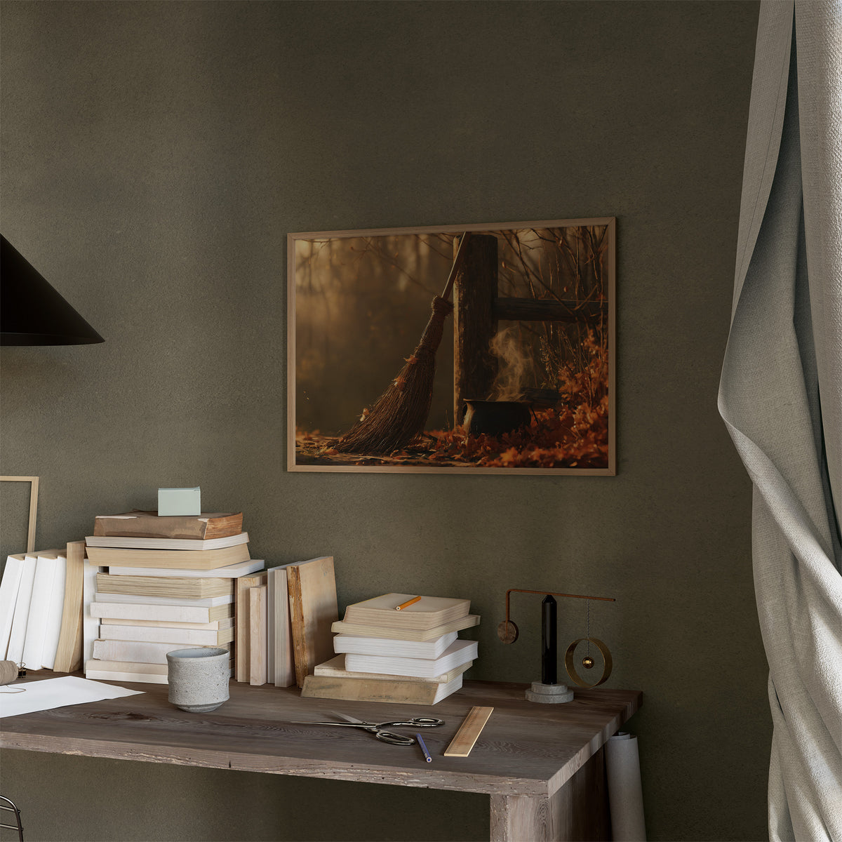 Where the Leaves Lie Down, a wooded path of fallen leaves in amber and rust under soft morning light, in a thin wood frame on a moss green wall above a desk stacked with books