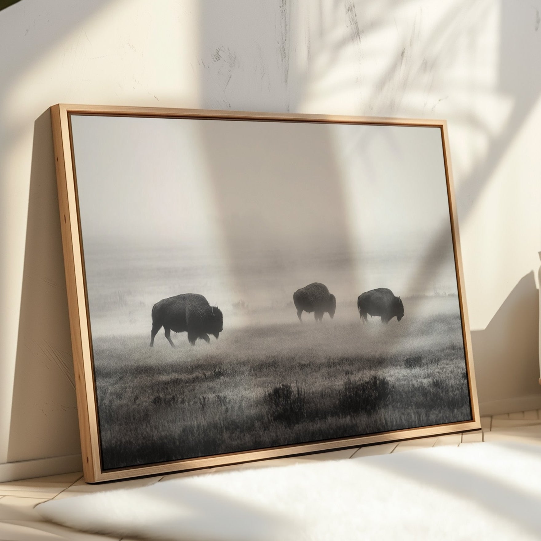 Framed artwork of three bison in a misty field on a wall in a room with sunlight filtering through.