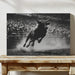 Black and white photo of a bull in mid-air over a wooden table