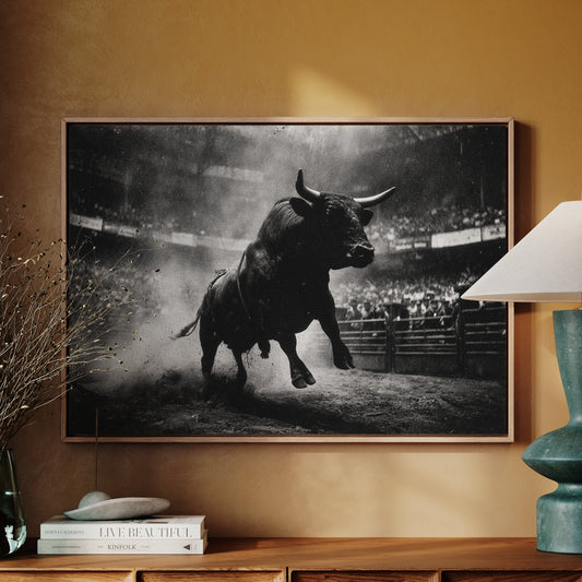 Framed black and white bull artwork on a wall above a wooden cabinet with decorative items.