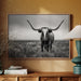 Framed black and white photo of a longhorn bull on a wall above a wooden cabinet with decor items.