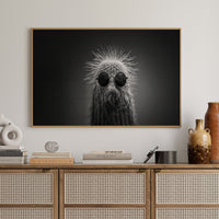 Wooden cabinet with decorative items and a framed black and white cactus print on a wall.
