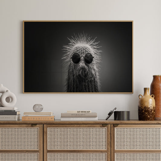 Wooden cabinet with decorative items and a framed black and white cactus print on a wall.