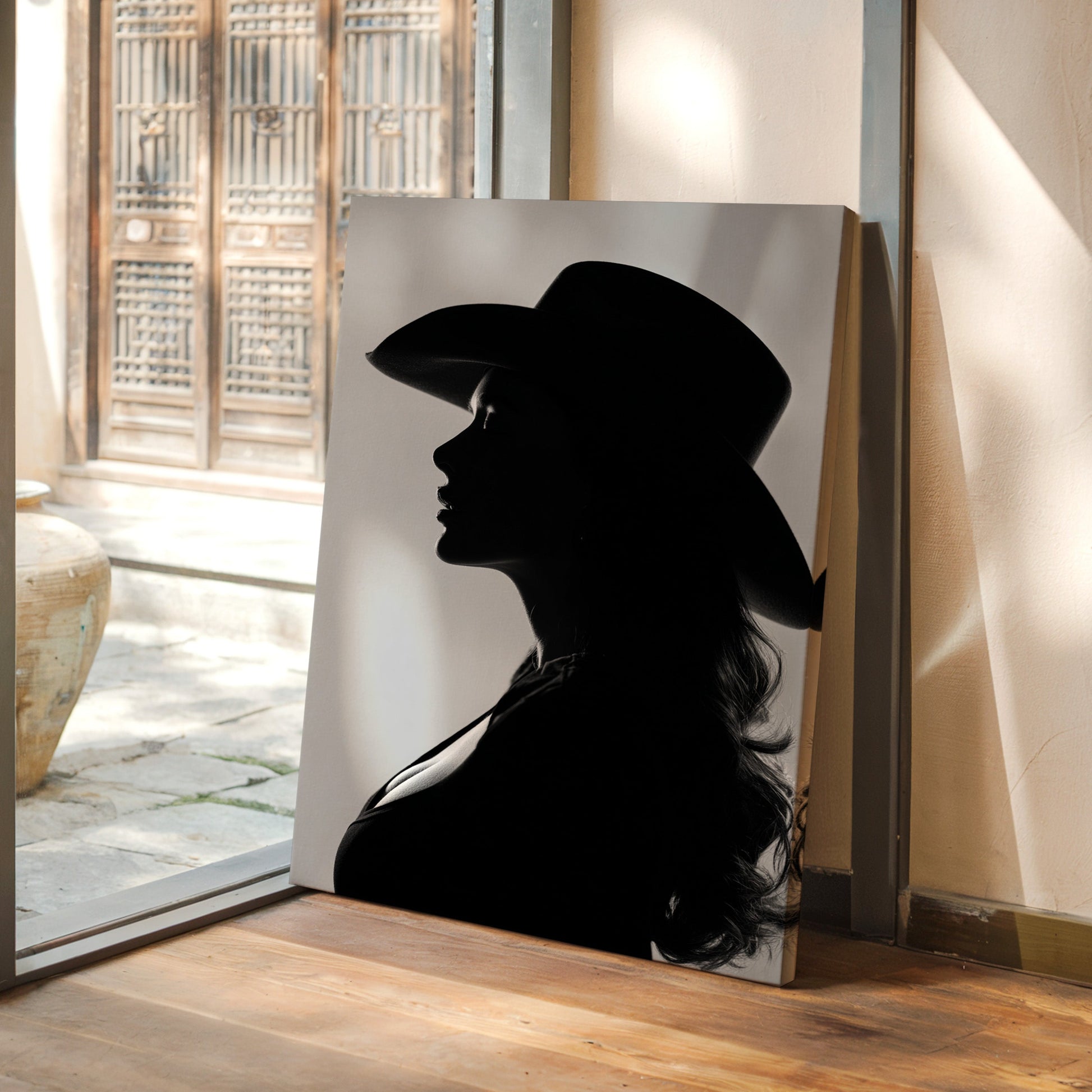 Silhouette of a person wearing a hat on a wall in a room with a view of a courtyard.