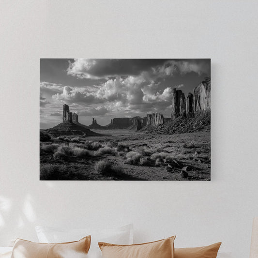 Black and white landscape print on a wall above a bed with beige pillows.