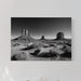 Desert landscape print on a wall above a bed with pillows and a lamp.