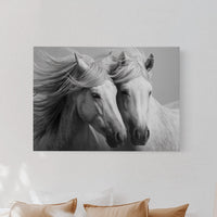 Canvas print of two horses on a wall above a bed with pillows and a lamp.