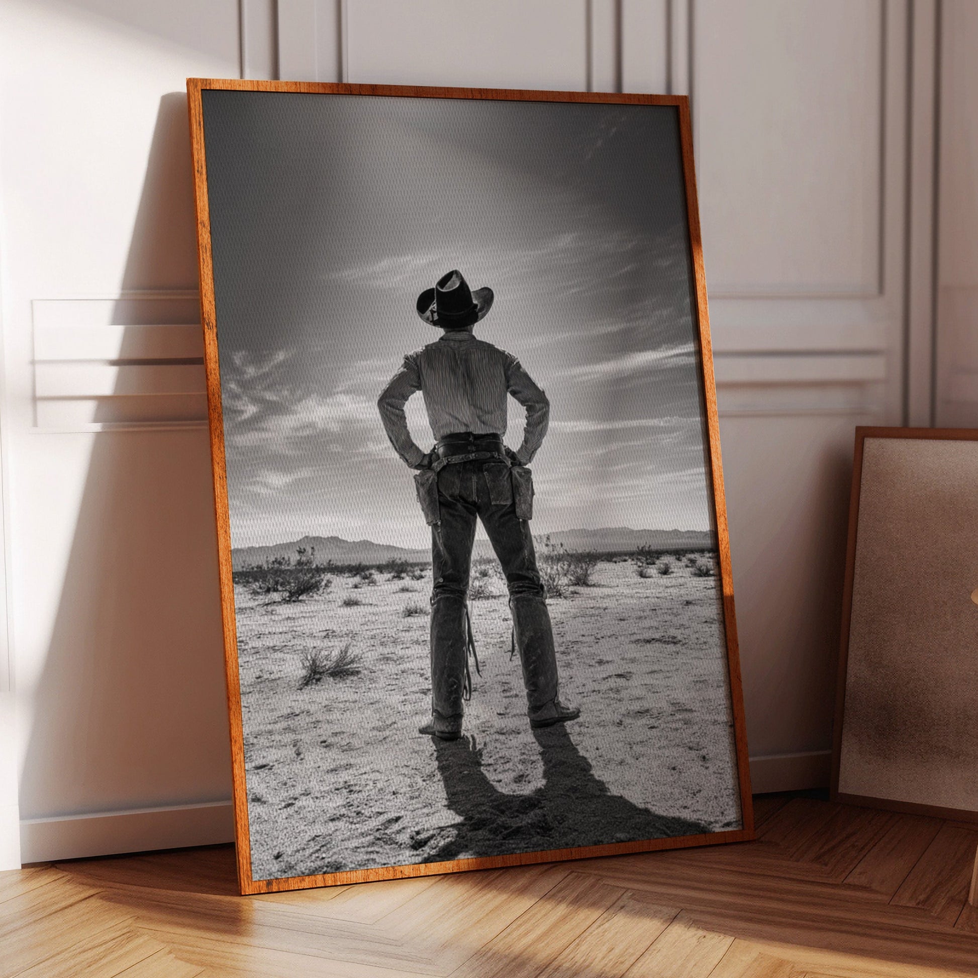 Framed black and white photograph of a cowboy in a desert landscape on a wooden floor.