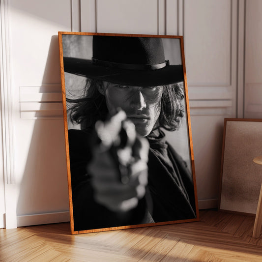 Framed black and white portrait of a person with a hat leaning against a wall.