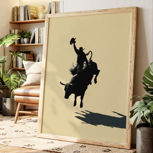 Framed artwork of a black silhouette of a person riding a bull on a beige wall in a living room.