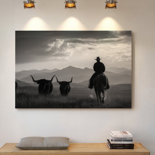 Framed artwork of a cowboy and two longhorns against a mountainous landscape, displayed on a wall above a wooden bench.