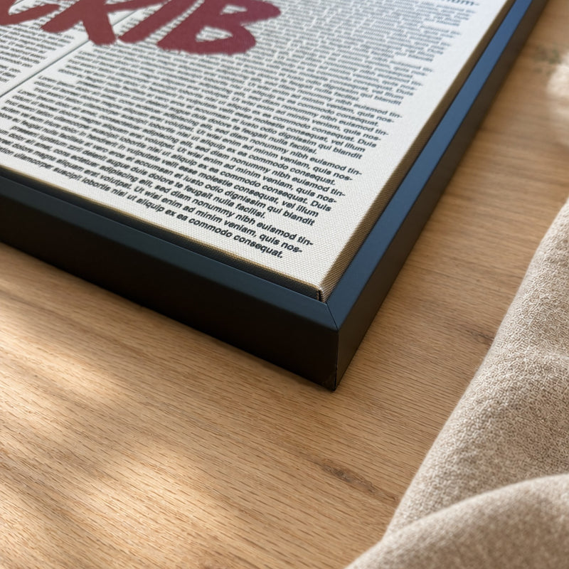 Corner of a black floater frame with the canvas set inside, resting on an oak table