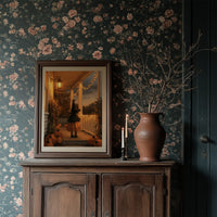 A Lantern for the Little Witch, a little witch in a pointed hat standing among pumpkins beneath string lights and a warm lantern glow, painted in orange, plum and deep shadow, in a dark frame on a wooden dresser against floral wallpaper