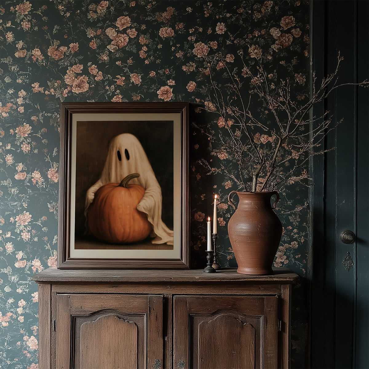 A Sheet Holds the Pumpkin Still, a pale draped figure holding a large orange pumpkin close, in a dark brown painted frame with a warm glow, in a dark wood frame on a floral wallpaper wall above a rustic cabinet and a vase