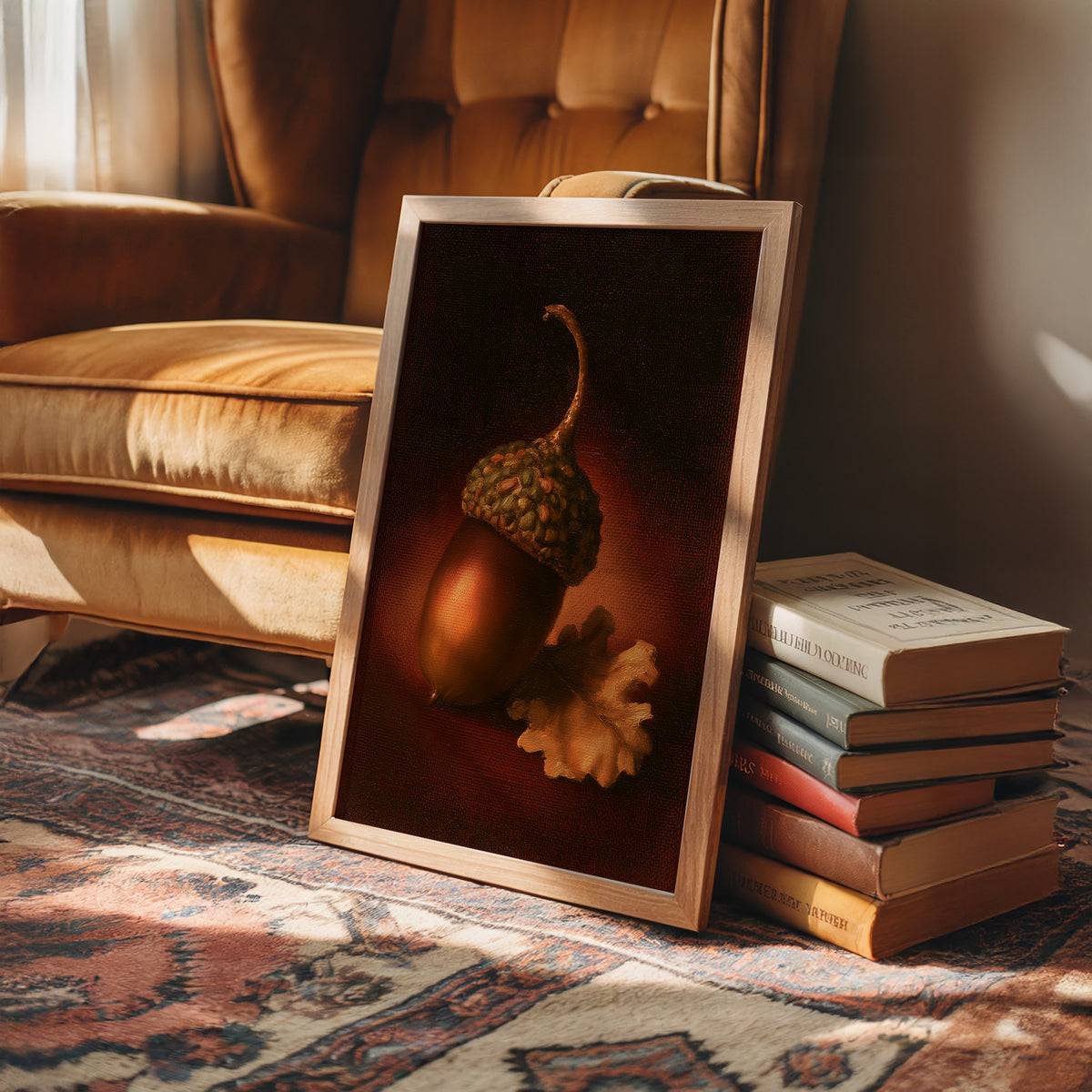 A Single Acorn in Candlelight, one acorn resting beside a curled oak leaf on a dark brown ground, lit from one side and painted in chestnut, amber and deep shadow, in a wood frame on a rug beside a leather armchair and a stack of books
