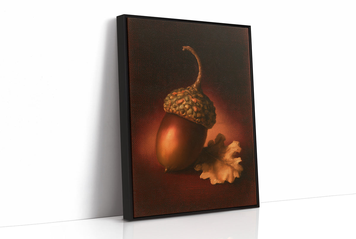 A Single Acorn in Candlelight, one acorn resting beside a curled oak leaf on a dark brown ground, lit from one side and painted in chestnut, amber and deep shadow, as a framed canvas in a black frame
