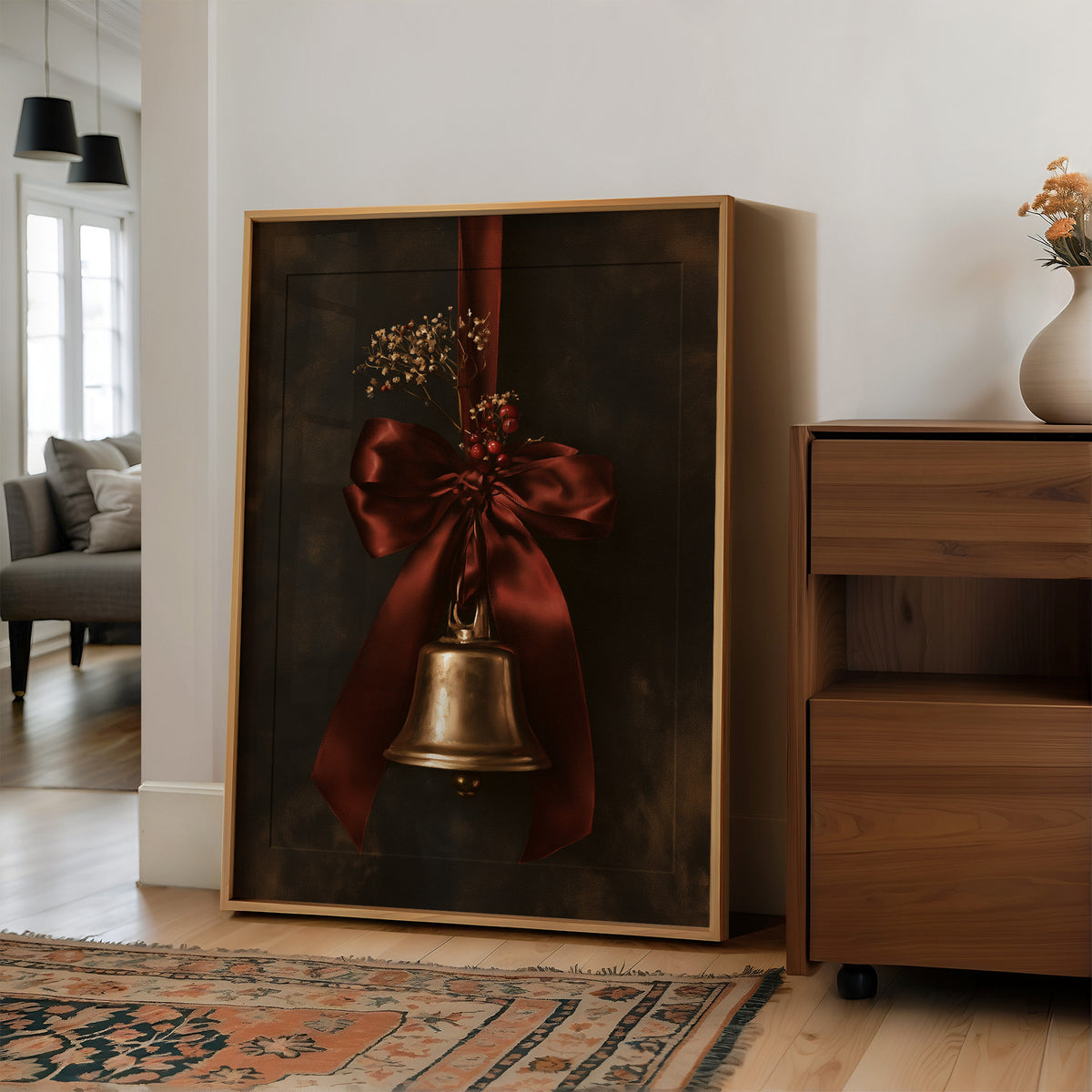 Bell Ringing for the Quiet Hour, a brass bell tied with a burgundy satin ribbon and dried sprigs, on a near black ground, in a wood frame on a wall beside a walnut cabinet and an open doorway