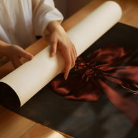 Bell Ringing for the Quiet Hour, a brass bell tied with a burgundy satin ribbon and dried sprigs, on a near black ground, as a matte poster, unframed