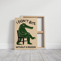 Bites Only With a Reason, a crocodile sitting upright in a plain wooden chair, in deep green on a cream ground, with a bold lettered line above reading I DON'T BITE and one below reading WITHOUT A REASON, on a gallery canvas with wrapped edges leaning against a white wall