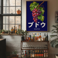 Clusters Heavy Over Midnight Water, a cluster of rose and purple grapes with green leaves hanging from a stem on a deep navy ground, with the Japanese katakana set in large white letters and the word GRAPES in small capitals beneath, in a wood frame on a brick wall above a bar cart of bottles and plants