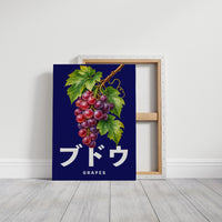 Clusters Heavy Over Midnight Water, a cluster of rose and purple grapes with green leaves hanging from a stem on a deep navy ground, with the Japanese katakana set in large white letters and the word GRAPES in small capitals beneath, on a gallery canvas with wrapped edges leaning against a white wall