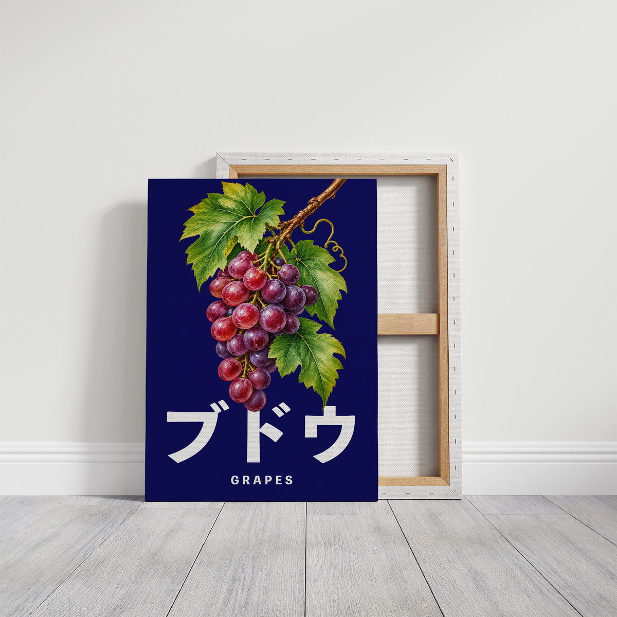 Clusters Heavy Over Midnight Water, a cluster of rose and purple grapes with green leaves hanging from a stem on a deep navy ground, with the Japanese katakana set in large white letters and the word GRAPES in small capitals beneath, on a gallery canvas with wrapped edges leaning against a white wall
