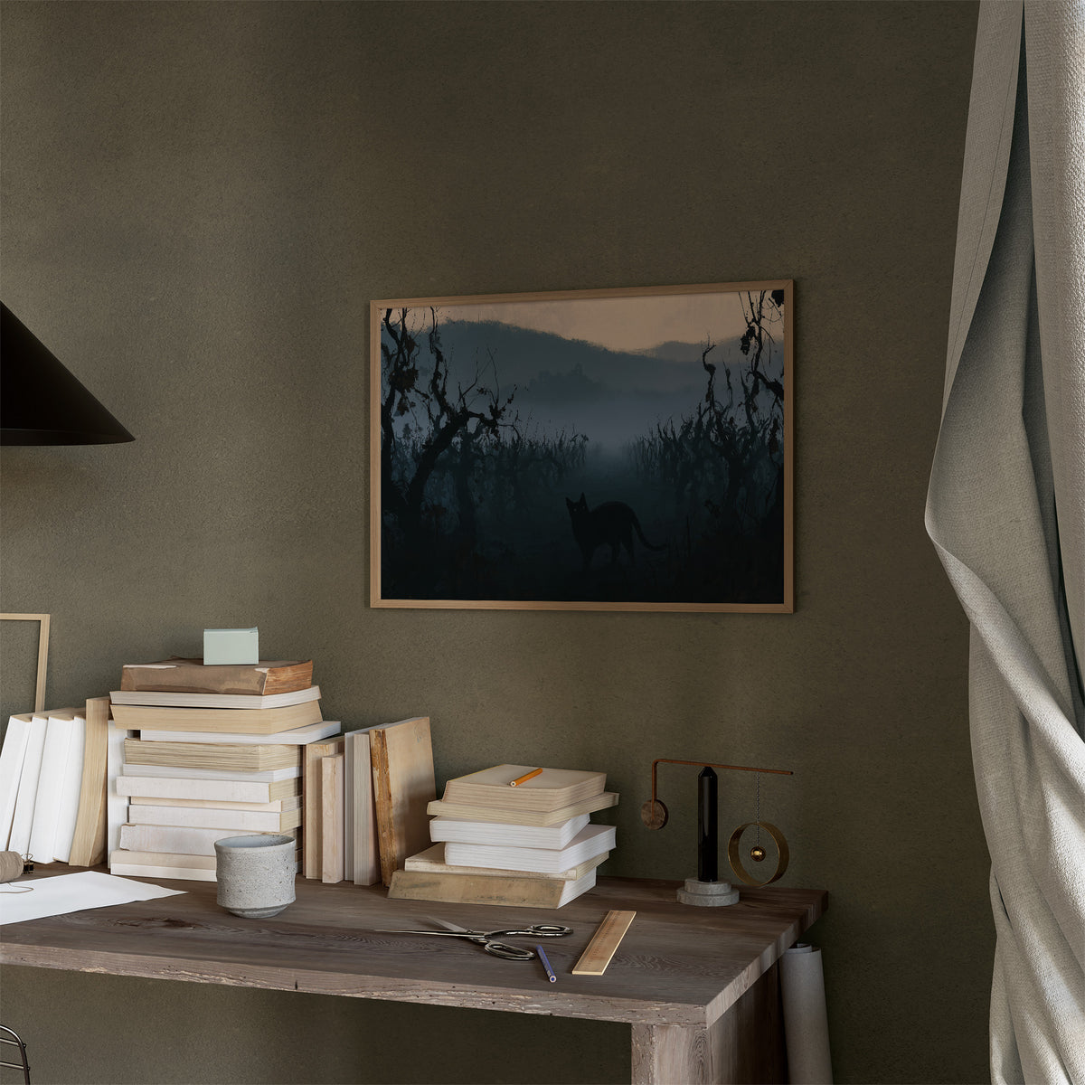Dusk Keeps the Hollow Quiet, a black cat silhouette standing in misty hills under gnarled trees, peach sky band at dusk, blue and charcoal palette, in a thin wood frame on a moss green wall above a desk stacked with books