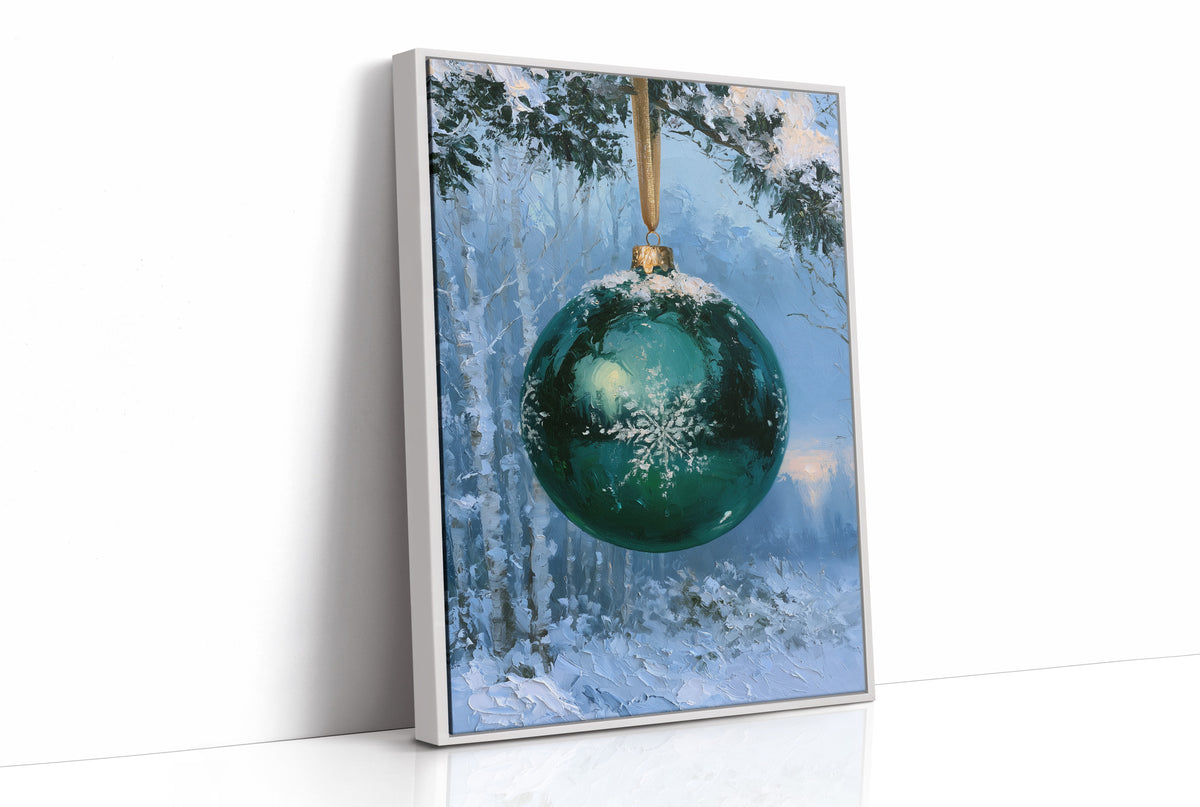 Emerald Light in the Snowlit Wood, a deep emerald glass bauble with a white snowflake on its face hangs from a gold cord in a snowy forest, with pale blue light and frosted pines behind, as a framed canvas in a white frame