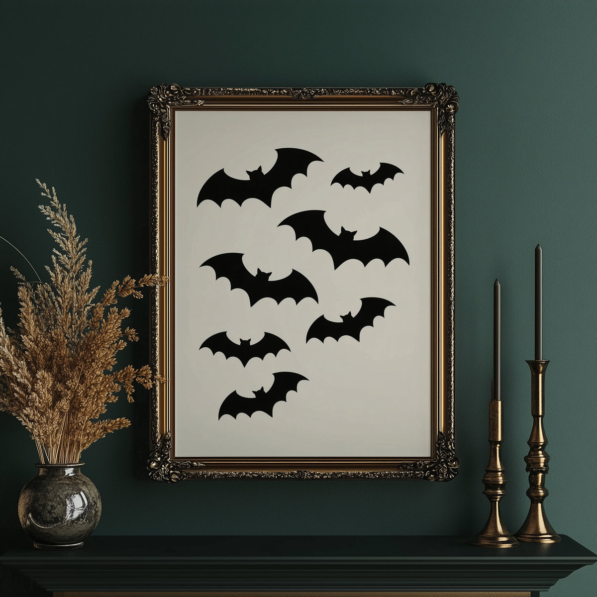 Evening Flight in Silhouette, a loose flock of black bat silhouettes spread across a cream ground in a simple, flat graphic arrangement, in an ornate gold frame on a deep green wall beside tall brass candlesticks