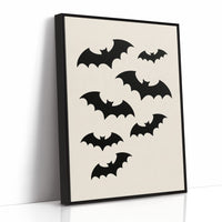 Evening Flight in Silhouette, a loose flock of black bat silhouettes spread across a cream ground in a simple, flat graphic arrangement, as a framed canvas in a black frame