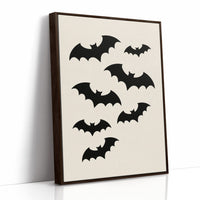 Evening Flight in Silhouette, a loose flock of black bat silhouettes spread across a cream ground in a simple, flat graphic arrangement, as a framed canvas in a brown frame